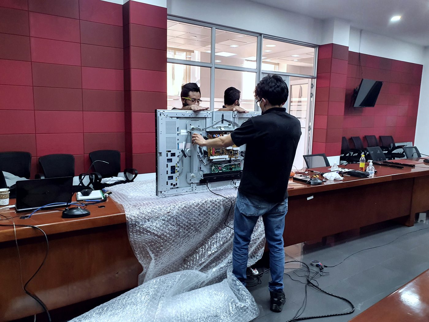 Técnicos de INNCET reparando una pantalla en una sala de juntas institucional