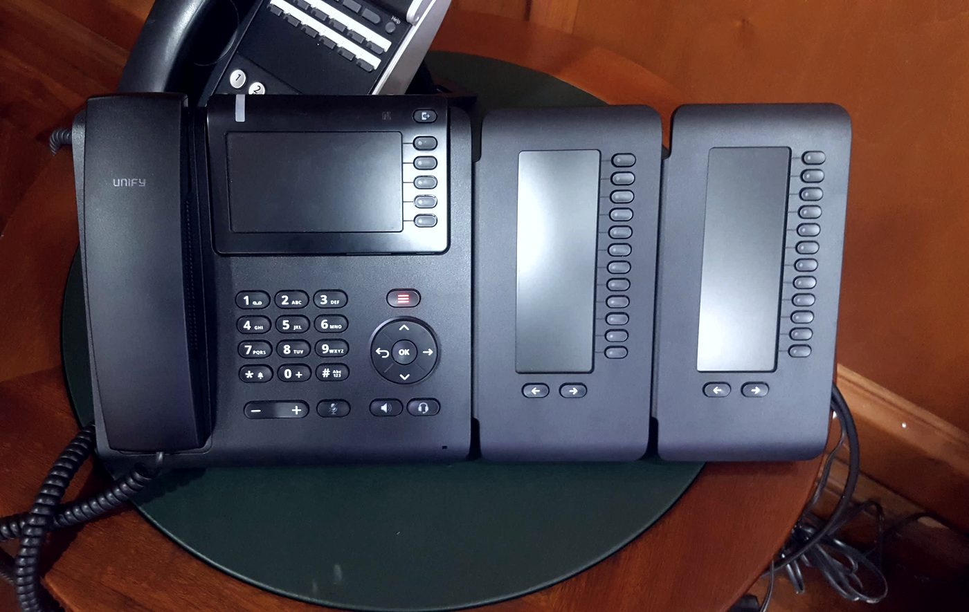 Teléfono IP Unify OpenScape con módulos de teclas adicionales instalado en un escritorio