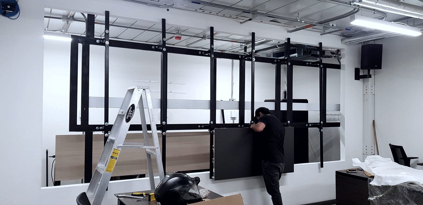Técnico de INNCET montando los paneles de un video wall en una sala de monitoreo